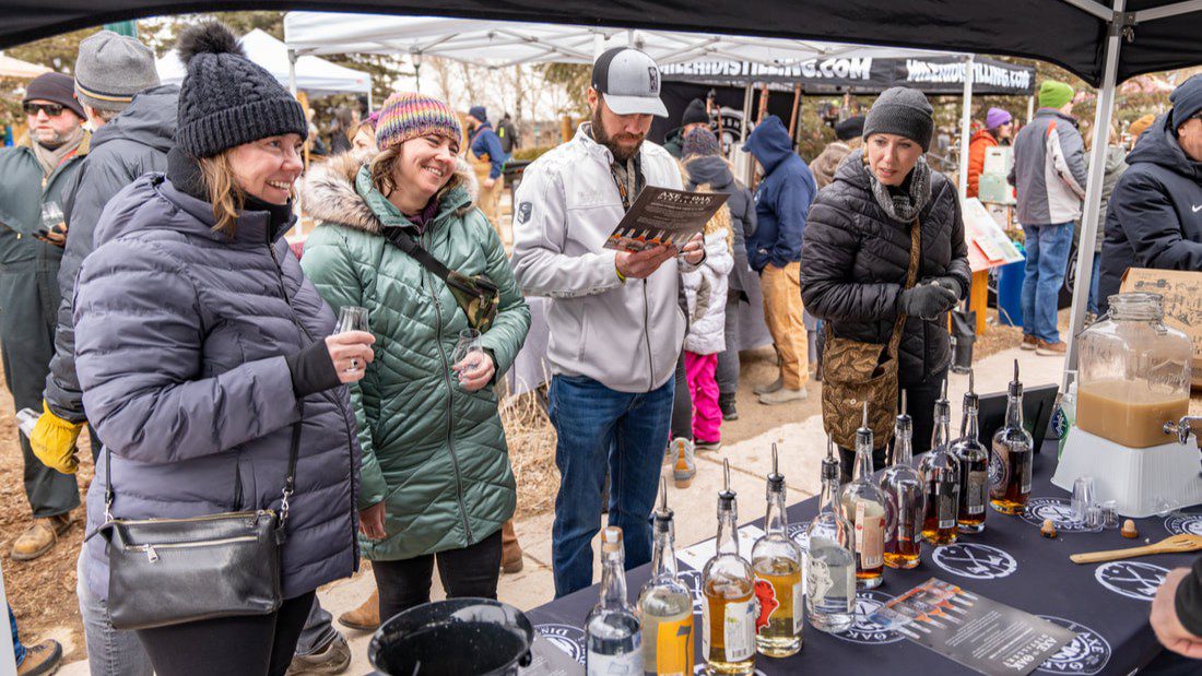 Attendees sampling whiskey tastings at a vendor table