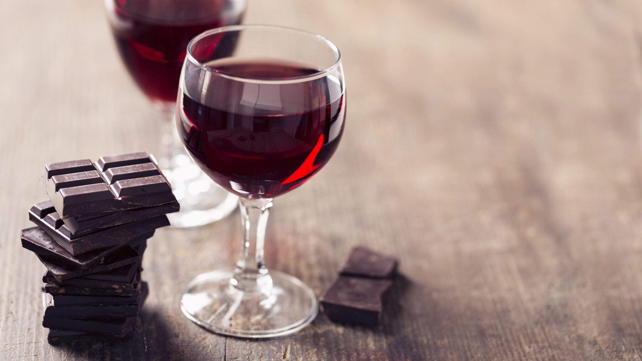 Glasses of red wine next to blocks of chocolate bars